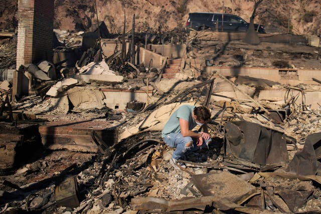 A man kneels as he sifts through the remains of a beach-front property