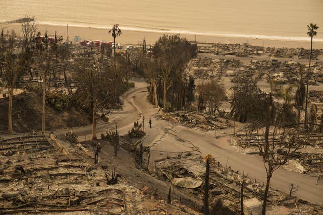 A person walks down a street in the aftermath of the Palisades Fire