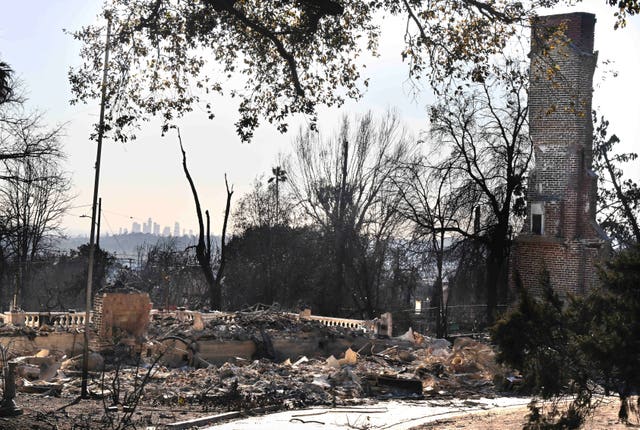 The Los Angeles skyline in the distance as a home burned by the Eaton Fire lies in ruins