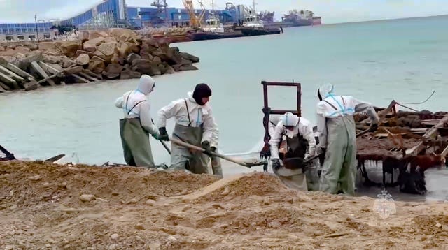 Russian workers in white suits clean up oil that spilled out of two storm-stricken tankers 