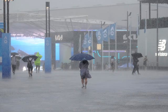 Spectators try to shelter from heavy rain at Melbourne Park 