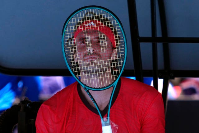 Stefanos Tsitsipas covers his face with his racket