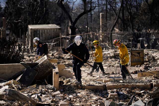 A search and rescue crew sifts through the wreckage of a home destroyed by the Eaton Fire in Altadena