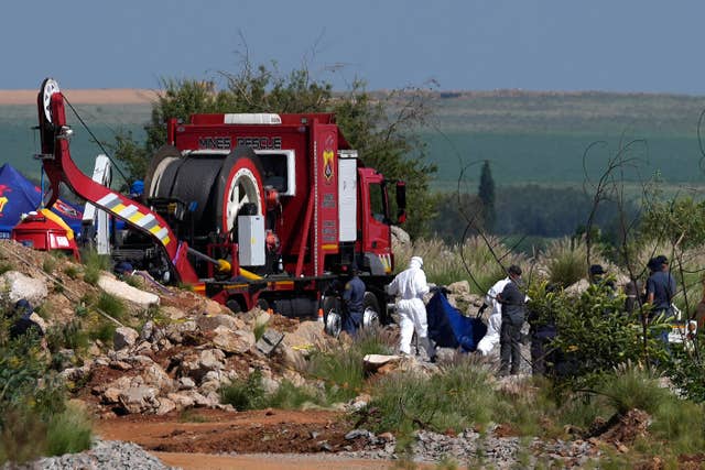 Forensic service workers carrying remains in blue body bags