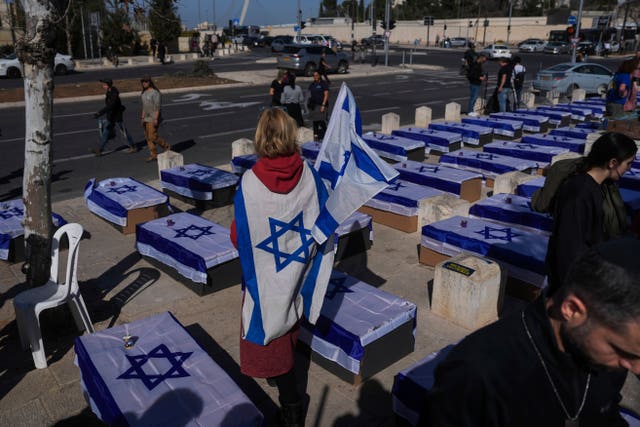 People stand by coffins covered with Israeli flags