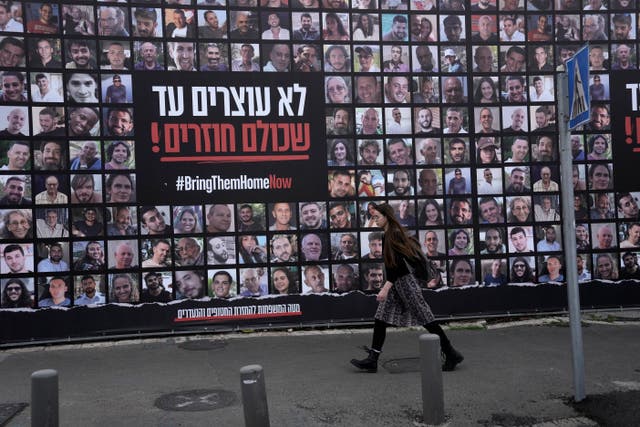 A woman in Jerusalem walks past photos of hostages held by Hamas in the Gaza Strip 