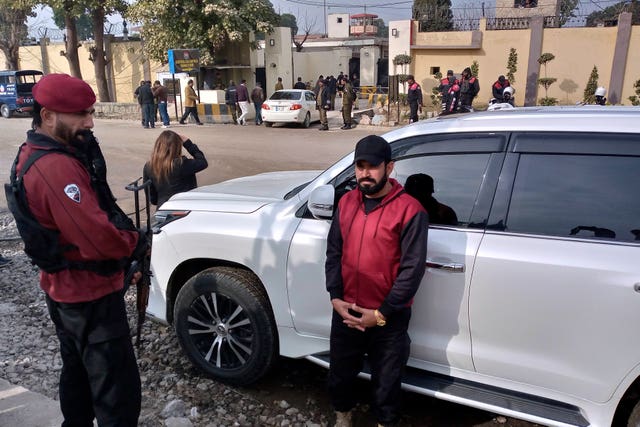 Security guards watch a vehicle carrying Bushra Bibi, wife of imprisoned former Prime Minister Imran Khan, as she arrives to hear verdict on corruption case in a court specially set up in Adiyala prison, in Rawalpindi,