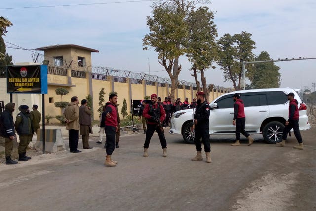 Security guards watch a vehicle carrying Bushra Bibi, wife of imprisoned former Prime Minister Imran Khan, as she arrives to hear verdict on corruption case in a court specially set up in Adiyala prison,