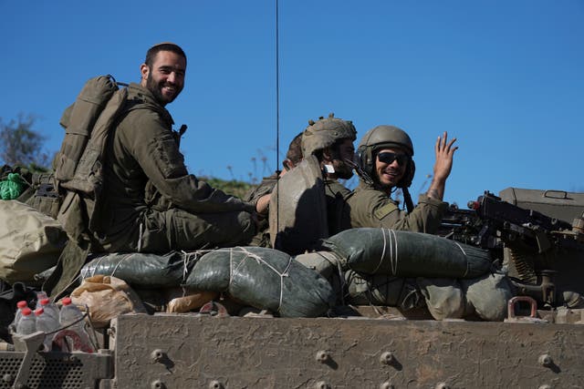 Israeli soldiers wave as they cross from the Gaza Strip into Israel 