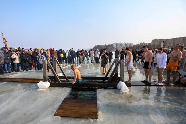 People look on as worshippers dip in icy water