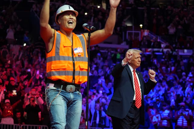 A Village Person and Donald Trump dance on stage 