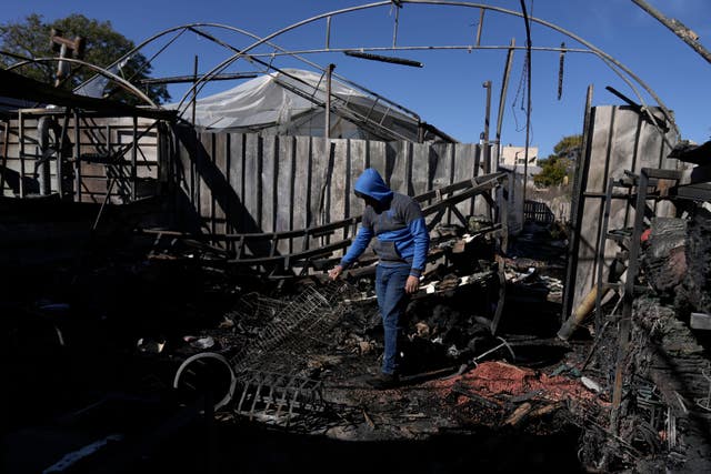 A Palestinian youth sifts through the aftermath of an attack by Israeli settlers in the West Bank village of Jinsafut