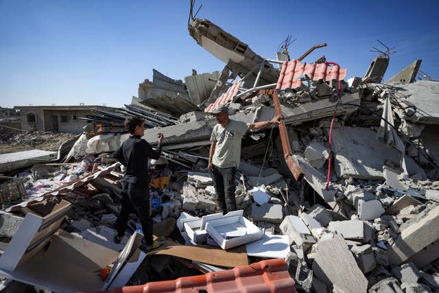 Murad Muqdad, center, stands amid the rubble of his destroyed home