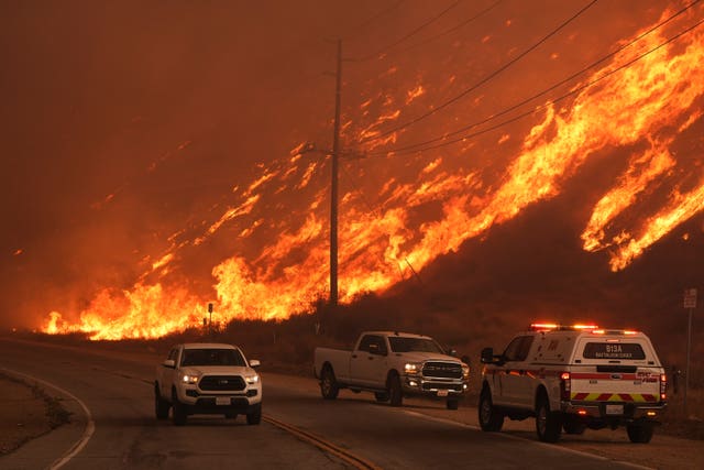 Fighter fighters monitor flames caused by the Hughes Fire along Castaic Lake in Castaic, California