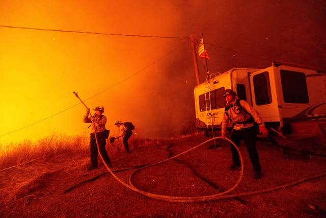 Firefighters spray water on the Hughes Fire in Castaic, California