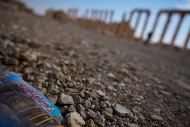 A flyer bearing the name “Palmyra” lies on the ground in the ancient city of Palmyra