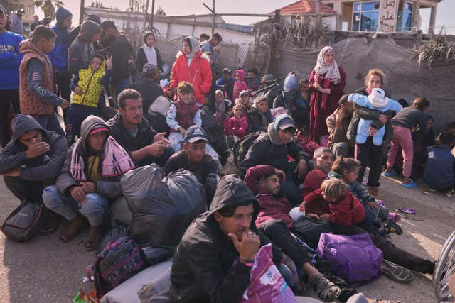 Palestinians wait next to their belongings in central Gaza, Saturday, Jan. 25, 2025, as the Israeli military is warning Palestinians not to return to northern Gaza.