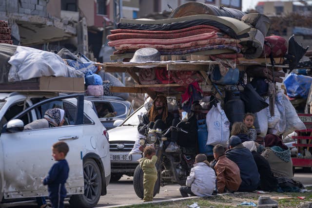 Palestinians gather with their belongings near a roadblock as they wait to return to their homes in northern Gaza 