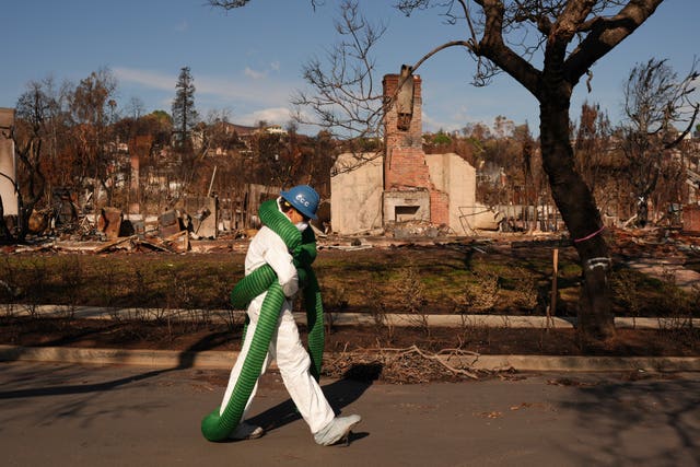 A workman walks in front of destroyed homes