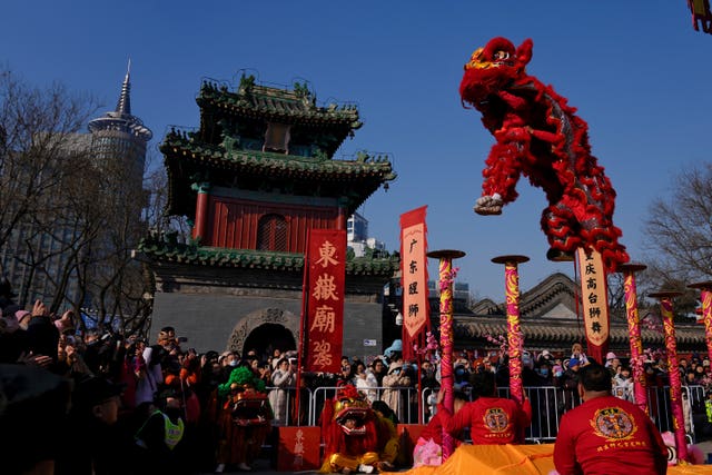 People watch as an artist performs an acrobatic lion dance at the Dongyue Temple