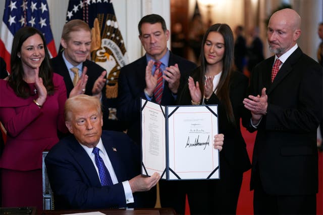 Donald Trump holds the document after signing the Laken Riley Act