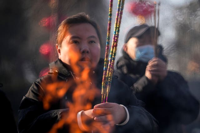 People holding incense offer prayer on the first day of the Chinese Lunar New Year at the Dongyue Temple in Beijing