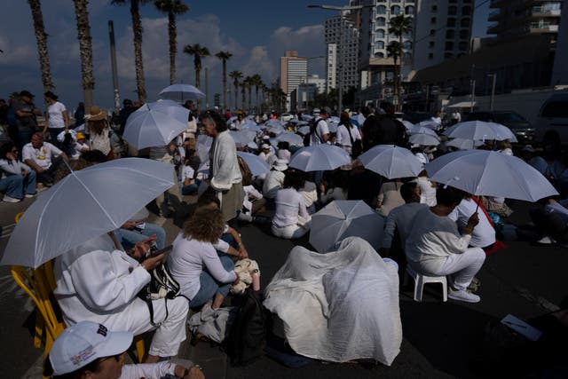 Activists sit on a road with white umbrellas during a protest calling for the release of hostages held in the Gaza Strip, in front of the US Embassy branch office in Tel Aviv on Friday