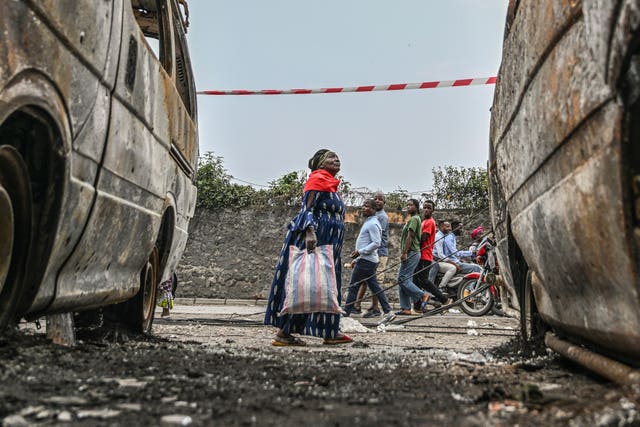 Residents walk by charred vehicles