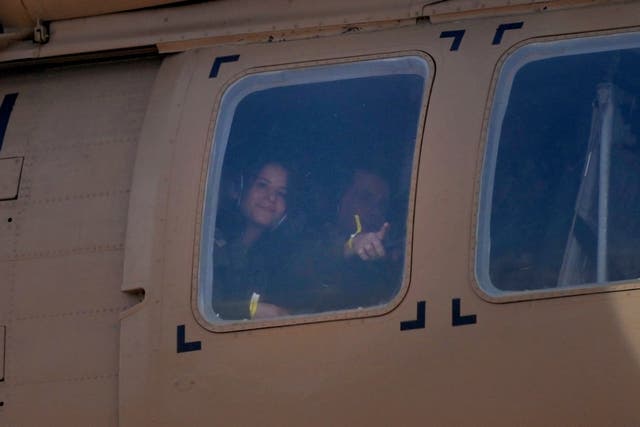 A hostage gestures through a window of a military helicopter