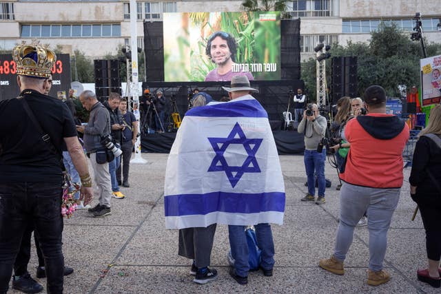 The people wrapped in the Israeli flag look at the screen