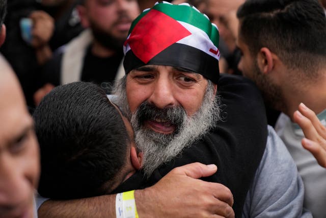 A Palestinian prisoner wearing a Palestinian flag headband is greeted as he exits a Red Cross bus after being released from Israeli prison 