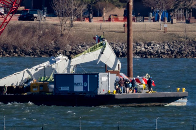 A piece of wreckage is lifted from the water on to a salvage vessel