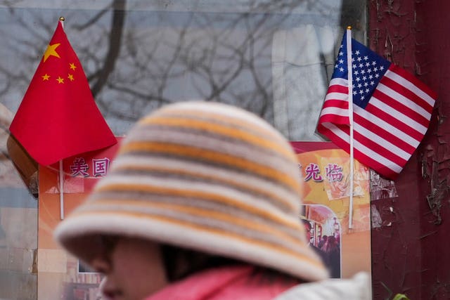 A woman in a hat walks past a Chinese and American flag