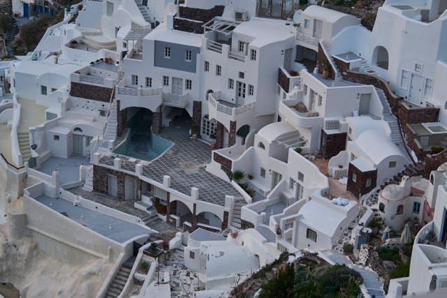 An empty swimming pool is seen in a group of clifftop buildings in the town of Oia on Santorini