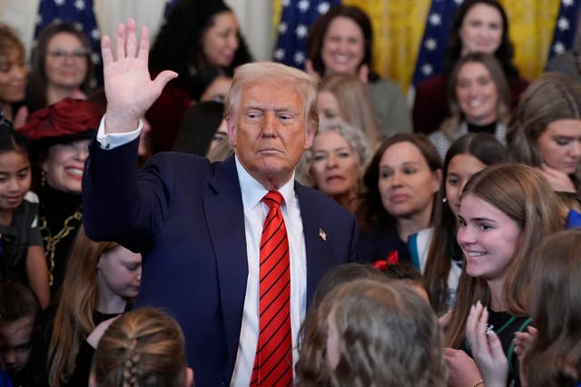 President Donald Trump waves after signing an executive order barring transgender female athletes from competing in women’s or girls’ sporting events, in the East Room of the White House