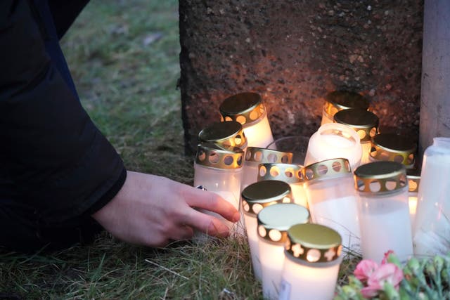 A man lights a candle at a makeshift memorial near the scene