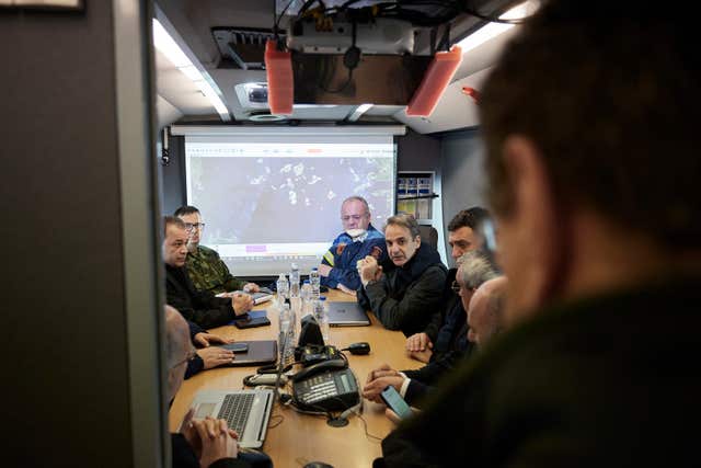 Kyriakos Mitsotakis, centre, gets an update during his visit to the temporary headquarters of emergency services on Santorini