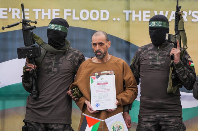 Eli Sharabi stands on a stage with Hamas fighters