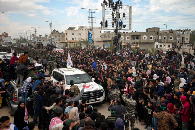 Palestinians gather as Hamas fighters escort Red Cross vehicles carrying the captives 