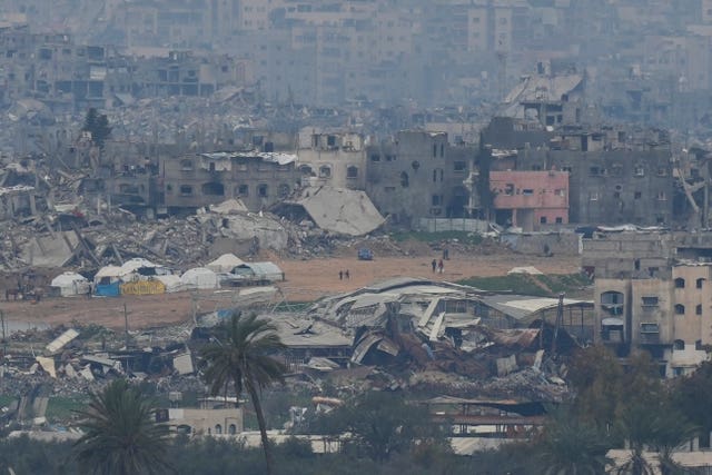 Palestinians are seen near buildings destroyed by Israeli bombardments inside the northern Gaza Strip as seen from southern Israel