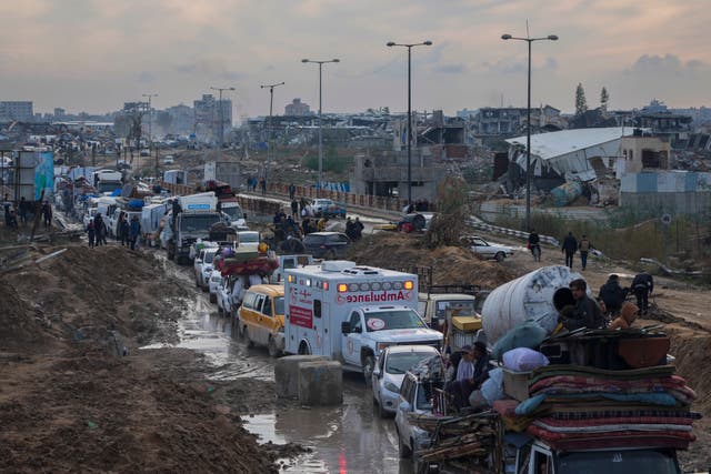 Displaced Palestinians, carrying their belongings in vehicles, wait at a security checkpoint