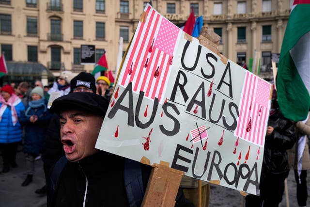 A man holds a poster reading USA: Out of Europe, during a protest against the Munich Security Conference