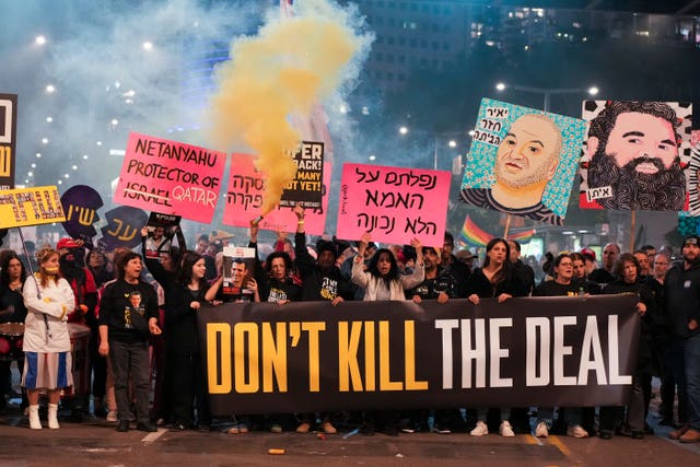 A crown marching with a banner that says 'don't kill the deal', others behind them hold smaller signs and pictures. Smoke is all around them