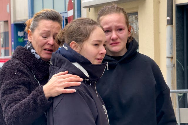 A woman and two teenage girls looking distressed