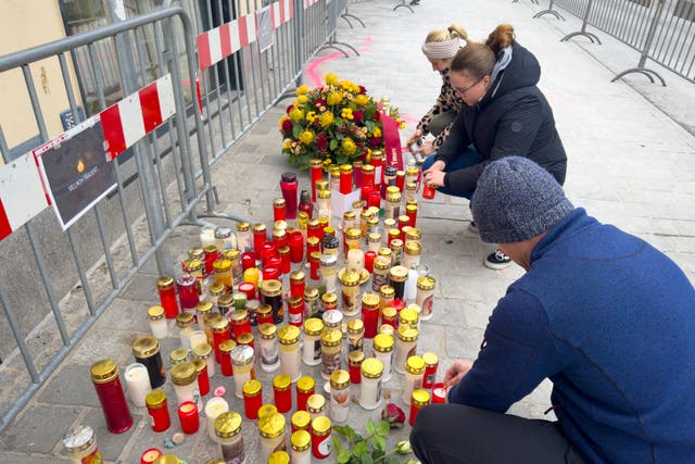 Candles are lit by people at a makeshift memorial