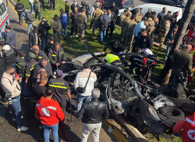 People gather round a burned car