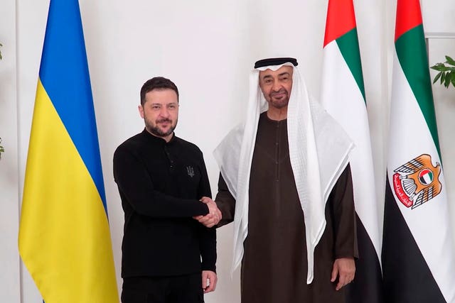 The two leaders shake hands before flags