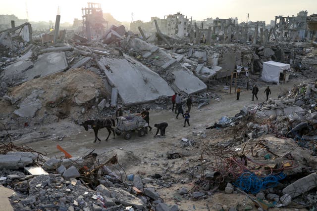 People walk amid destruction caused by the Israeli air and ground offensive in Jabaliya, Gaza Strip