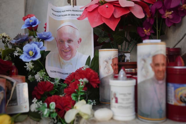 Candles and a photo of Pope Francis are seen in front of a hospital 