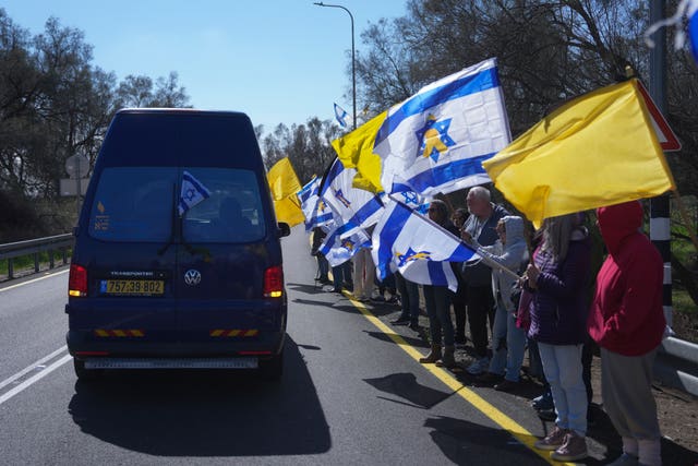 Mourners wave Israeli flags as the car carrying the coffin of former Israeli hostage Oded Lifshitz passes by